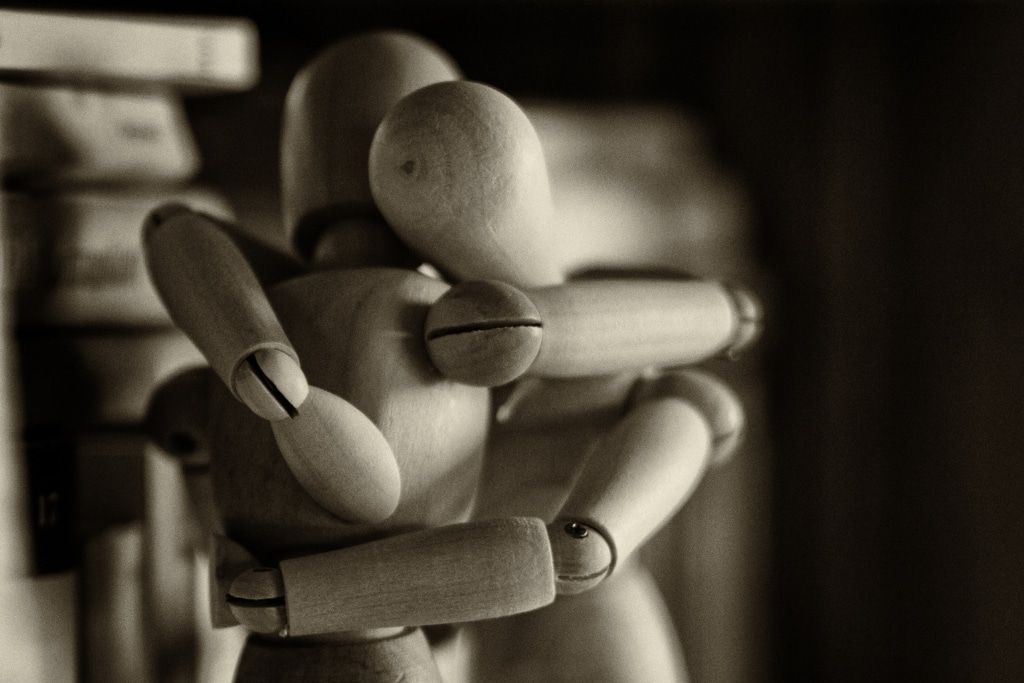 two wooden figures embracing