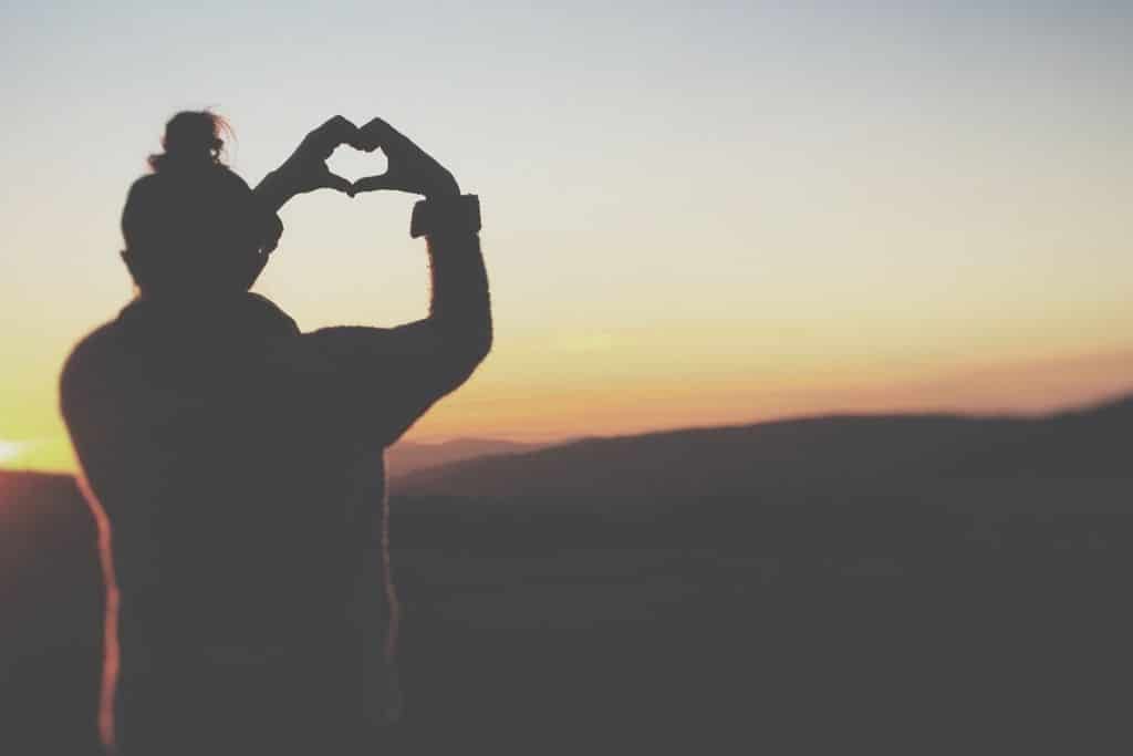 lady with hands in heart shape at sunset