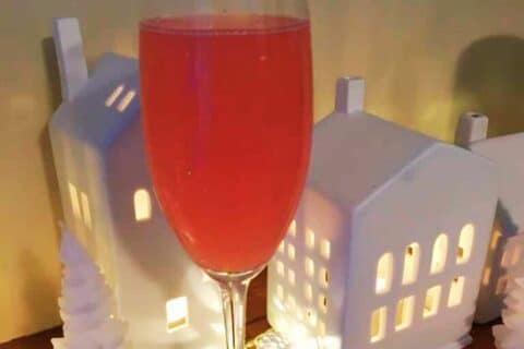 Pink watermelon drink in a champaign flute surrounded by candles