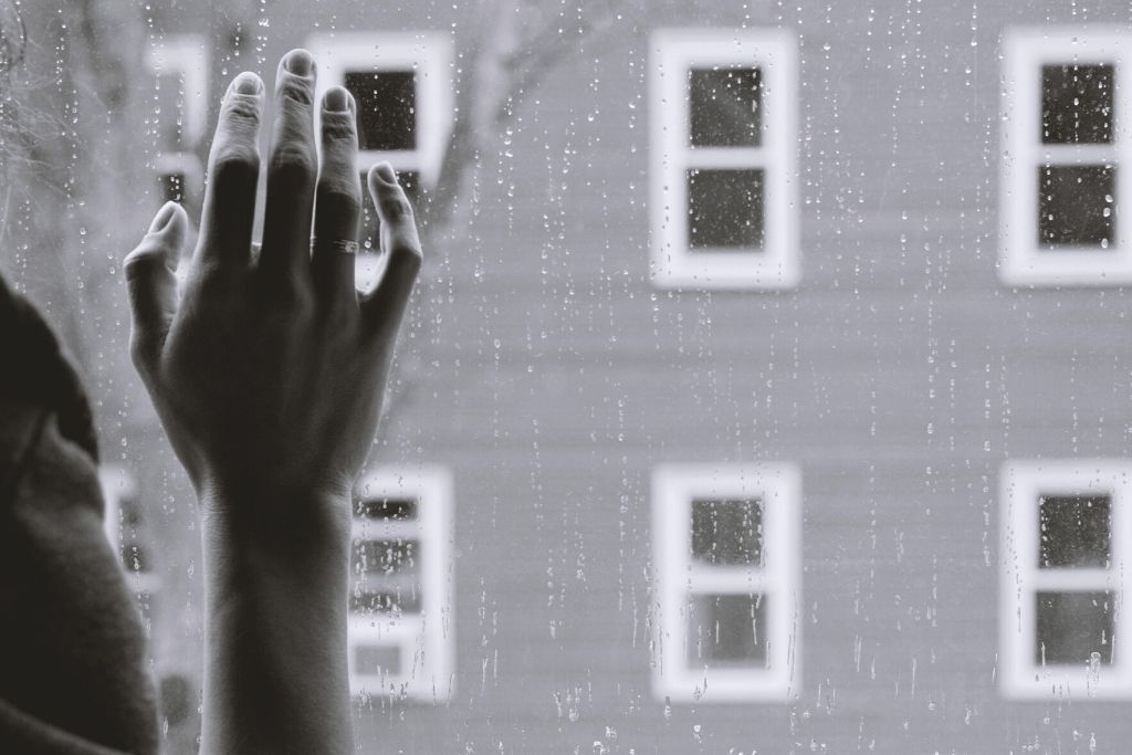 woman's hand on rain covered window