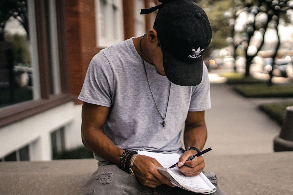 guy in cap writing in notebook